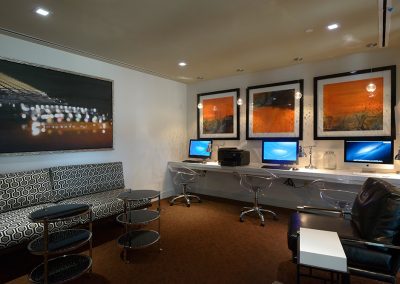 Row of computers with large framed images on the wall behind them.